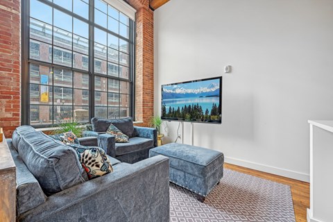 a living room with a large window and a couch and a chair at Riverwalk Apartments, Lawrence, MA